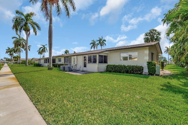 back of property featuring stucco siding, a yard, and central AC