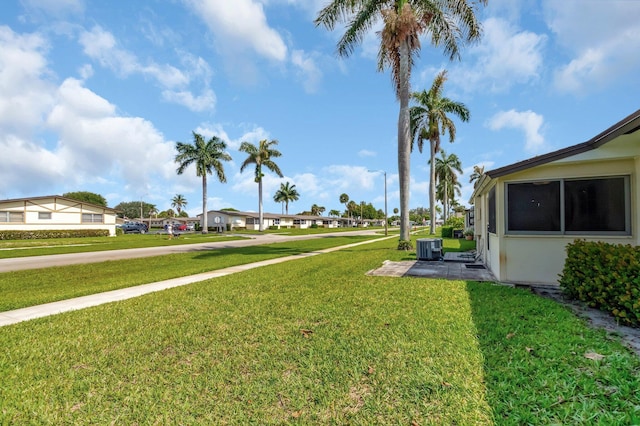 view of green lawn with central air condition unit and a residential view