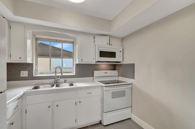kitchen featuring white appliances, a sink, decorative backsplash, light countertops, and white cabinetry