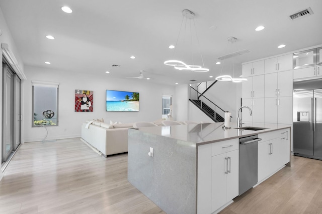 13444 Bernoulli Way, Palm Beach Gardens, FL 33418 - kitchen with stainless steel appliances, a sink, an island with sink, light wood finished floors, and hanging light fixtures
