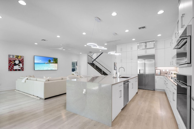 13444 Bernoulli Way, Palm Beach Gardens, FL 33418 - kitchen featuring appliances with stainless steel finishes, a sink, light wood-type flooring, white cabinetry, and recessed lighting