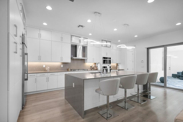 13444 Bernoulli Way, Palm Beach Gardens, FL 33418 - kitchen featuring wall chimney range hood, a sink, gas cooktop, light wood-type flooring, and recessed lighting