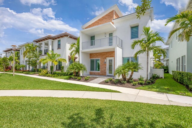 13444 Bernoulli Way, Palm Beach Gardens, FL 33418 - view of front of home featuring stucco siding, a front lawn, and a balcony