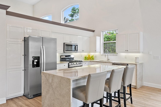 8405 Legend Club Dr, West Palm Beach, FL 33412 - kitchen with appliances with stainless steel finishes, a sink, a high ceiling, light wood-type flooring, and white cabinets