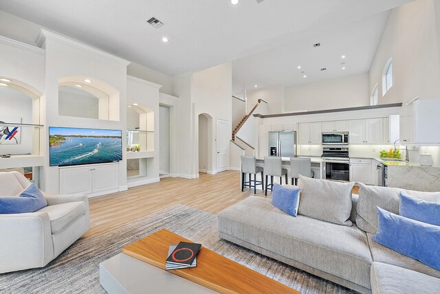 8405 Legend Club Dr, West Palm Beach, FL 33412 - living area featuring light wood-type flooring, arched walkways, recessed lighting, a towering ceiling, and crown molding