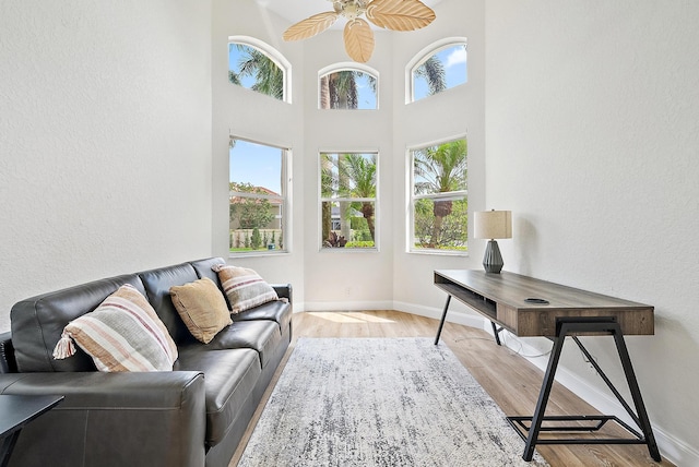 8405 Legend Club Dr, West Palm Beach, FL 33412 - living room with light wood-style flooring, ceiling fan, baseboards, a textured wall, and a high ceiling