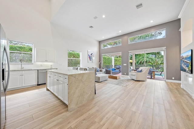 8405 Legend Club Dr, West Palm Beach, FL 33412 - kitchen featuring a high ceiling, stainless steel appliances, white cabinets, light stone countertops, and light wood-style flooring