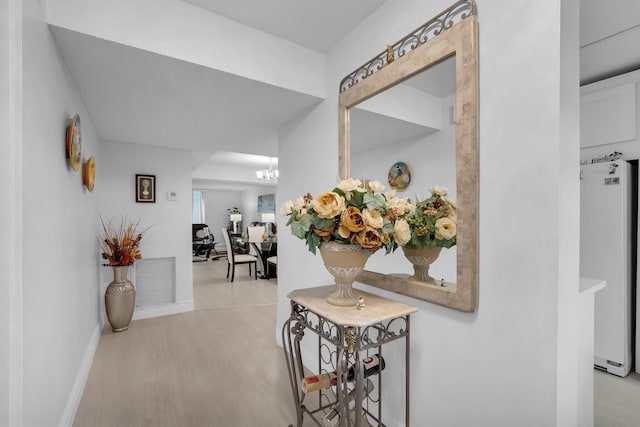 23247 Barwood Ln Unit 305, Boca Raton, FL 33428 - hallway with light wood-style flooring, baseboards, and a chandelier
