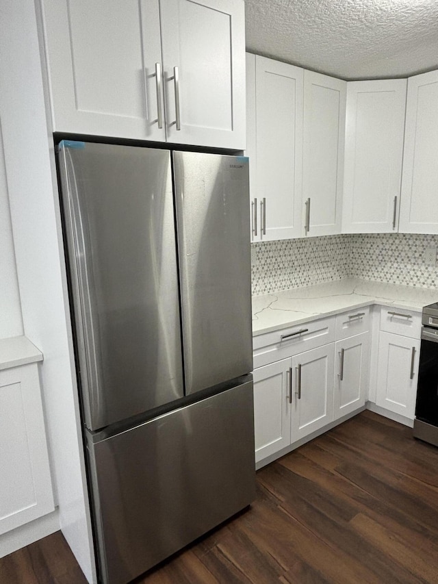 7690 Tahiti Ln Unit 102, Lake Worth, FL 33467 - kitchen with appliances with stainless steel finishes, white cabinetry, dark wood-style flooring, light stone counters, and backsplash