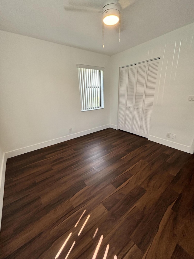 7690 Tahiti Ln Unit 102, Lake Worth, FL 33467 - unfurnished bedroom with dark wood-style floors, baseboards, a closet, and ceiling fan