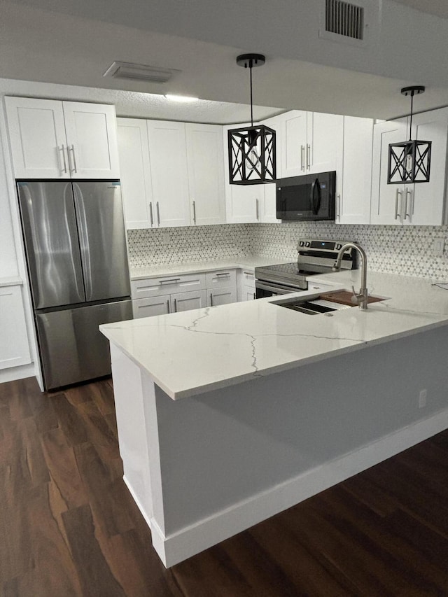 7690 Tahiti Ln Unit 102, Lake Worth, FL 33467 - kitchen featuring appliances with stainless steel finishes, a peninsula, light stone counters, dark wood finished floors, and white cabinetry