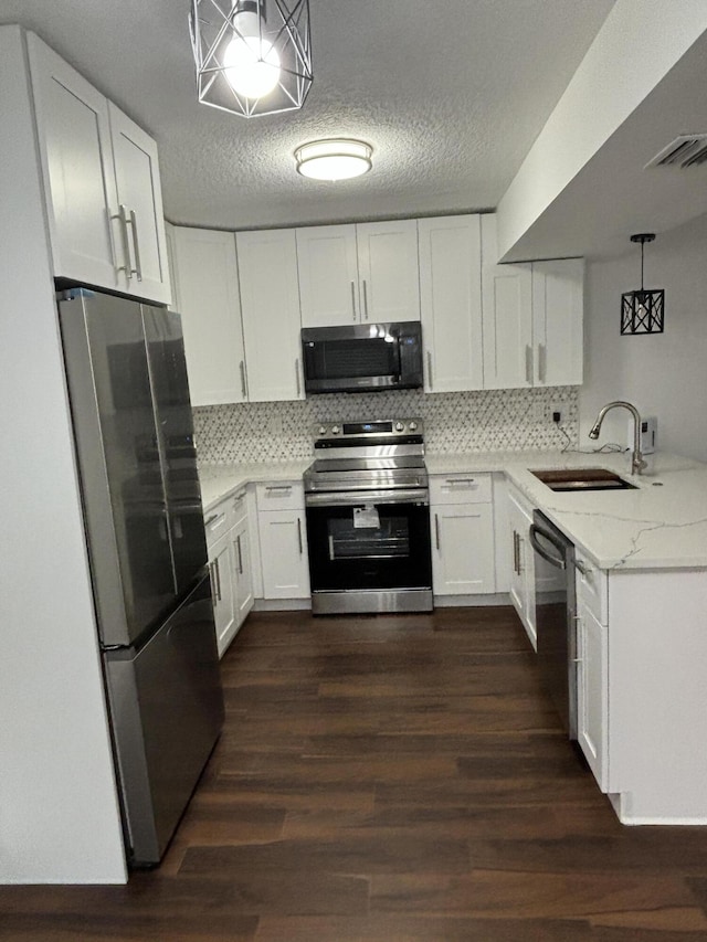 7690 Tahiti Ln Unit 102, Lake Worth, FL 33467 - kitchen featuring stainless steel appliances, a sink, white cabinets, dark wood-style flooring, and a textured ceiling