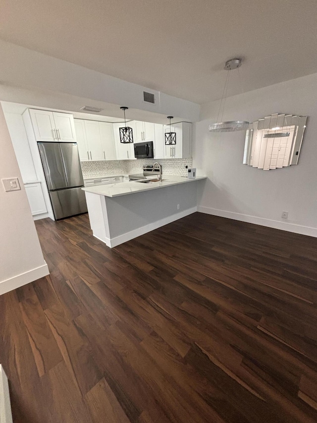 7690 Tahiti Ln Unit 102, Lake Worth, FL 33467 - kitchen with appliances with stainless steel finishes, a peninsula, tasteful backsplash, and dark wood-type flooring