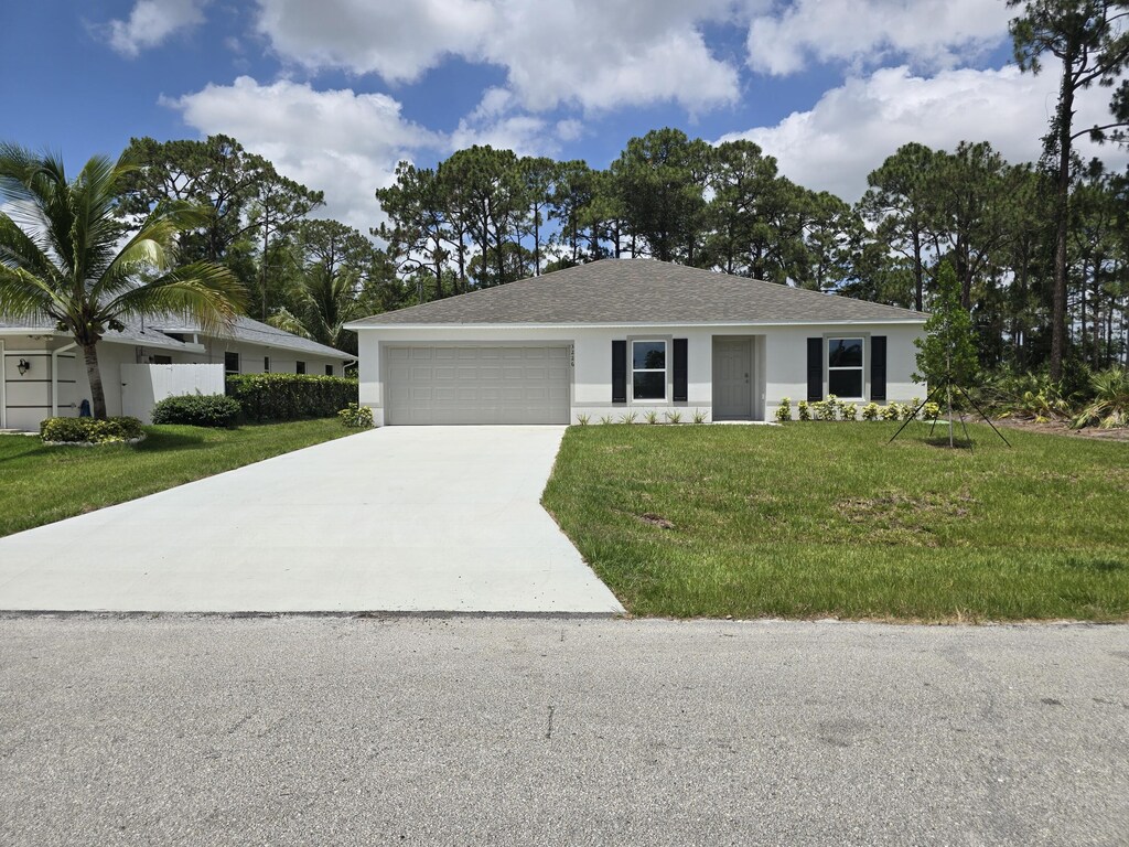 3226 SW Nutley St, Port Saint Lucie, FL 34953 - ranch-style house featuring concrete driveway, a garage, a front yard, stucco siding, and roof with shingles