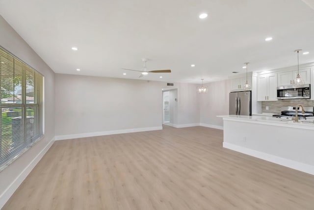 unfurnished living room with light wood-type flooring, baseboards, recessed lighting, and a ceiling fan