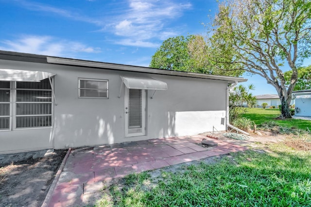 rear view of house with stucco siding and a patio