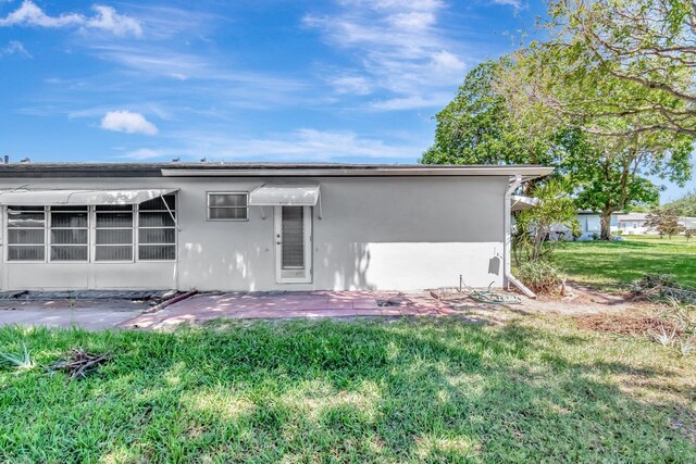 rear view of property with a yard, stucco siding, and a patio area