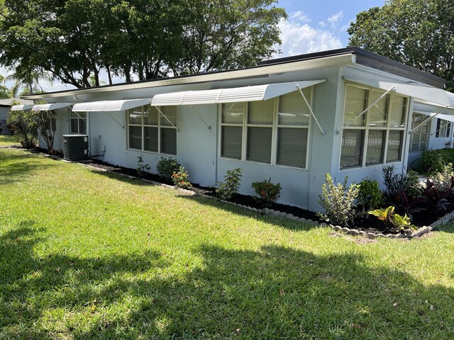 470 High Point Dr Unit A, Delray Beach, FL 33445 - view of front of house with central air condition unit, a front yard, and stucco siding