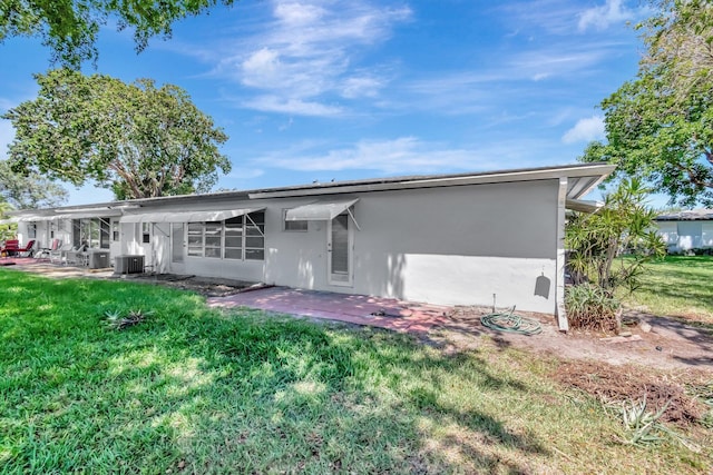 back of house featuring stucco siding, a patio, a lawn, and central AC unit