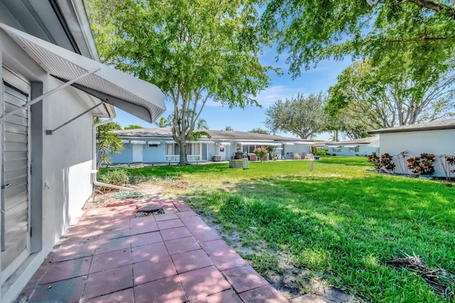 view of green lawn with a patio area