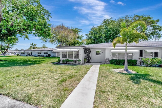 ranch-style house with stucco siding and a front lawn