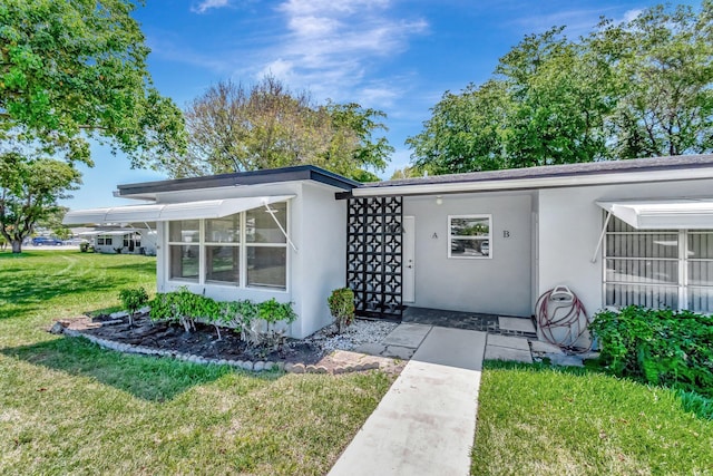doorway to property featuring a lawn and stucco siding