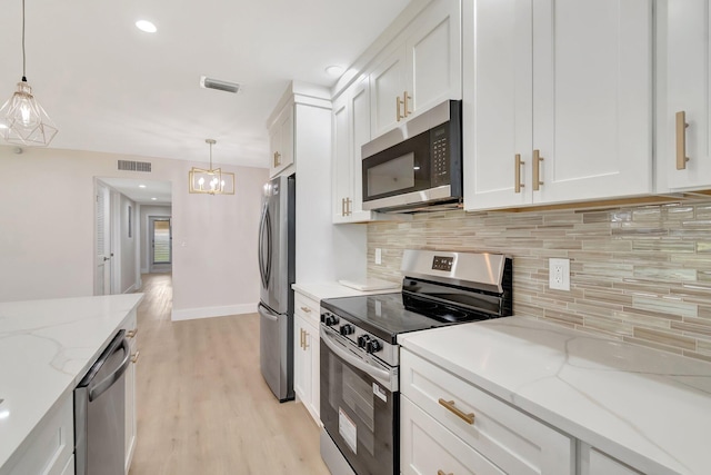 kitchen featuring appliances with stainless steel finishes, backsplash, white cabinetry, pendant lighting, and light wood-style flooring