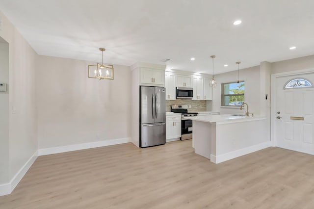 kitchen featuring appliances with stainless steel finishes, a chandelier, light wood-type flooring, baseboards, and a peninsula