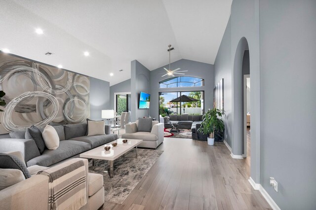 10393 Lexington Cir S, Boynton Beach, FL 33436 - living room with arched walkways, ceiling fan, light wood-style floors, high vaulted ceiling, and baseboards