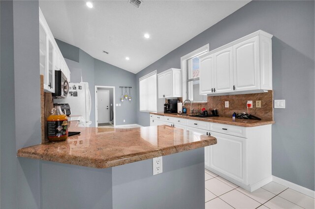 10393 Lexington Cir S, Boynton Beach, FL 33436 - kitchen with stainless steel microwave, a peninsula, a sink, vaulted ceiling, and white cabinets