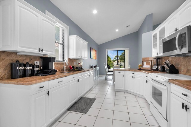 10393 Lexington Cir S, Boynton Beach, FL 33436 - kitchen with white electric range oven, stainless steel microwave, a sink, vaulted ceiling, and decorative backsplash