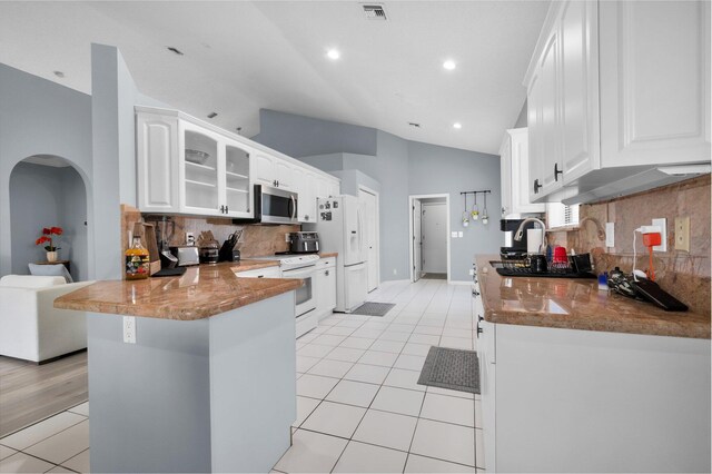 10393 Lexington Cir S, Boynton Beach, FL 33436 - kitchen featuring white appliances, light tile patterned floors, a peninsula, vaulted ceiling, and tasteful backsplash