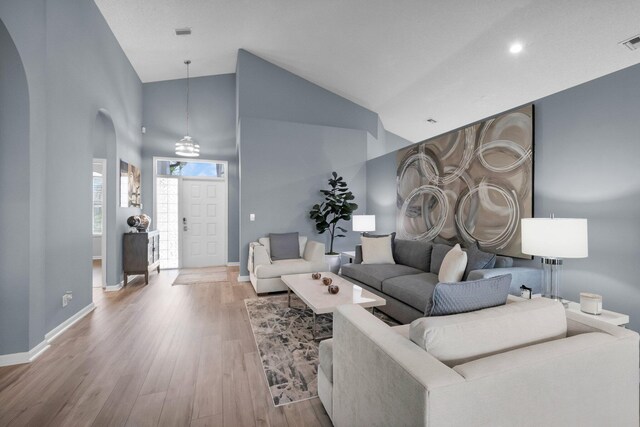 10393 Lexington Cir S, Boynton Beach, FL 33436 - living room featuring arched walkways, wood finished floors, baseboards, and high vaulted ceiling