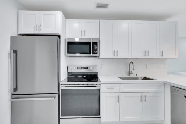 5305 Cleveland Rd, Delray Beach, FL 33484 - kitchen with stainless steel appliances, a sink, white cabinetry, and light countertops