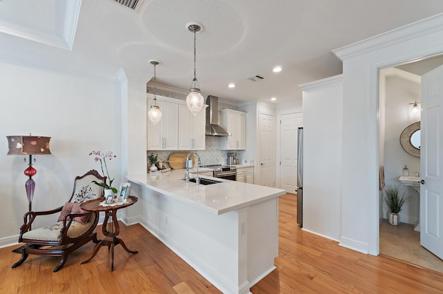 4608 Cadiz Cir, Palm Beach Gardens, FL 33418 - kitchen with wall chimney exhaust hood, light countertops, a peninsula, tasteful backsplash, and appliances with stainless steel finishes