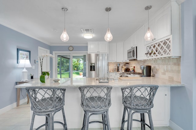 kitchen featuring appliances with stainless steel finishes, a peninsula, backsplash, white cabinetry, and baseboards