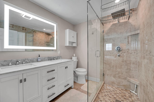 bathroom with a stall shower, double vanity, and toilet