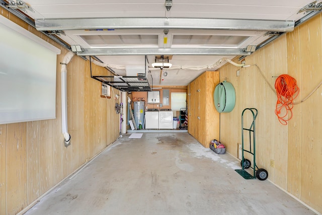 garage with water heater, washing machine and dryer, wood walls, and a garage door opener