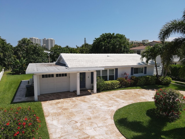 ranch-style home with an attached garage, driveway, a front yard, and stucco siding
