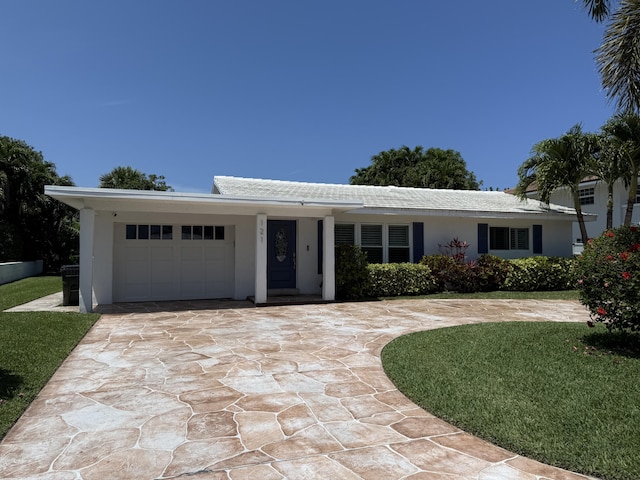 single story home featuring a garage, curved driveway, stucco siding, and a front lawn