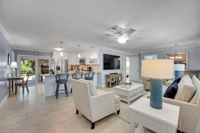 living room featuring crown molding, ceiling fan, a chandelier, and baseboards