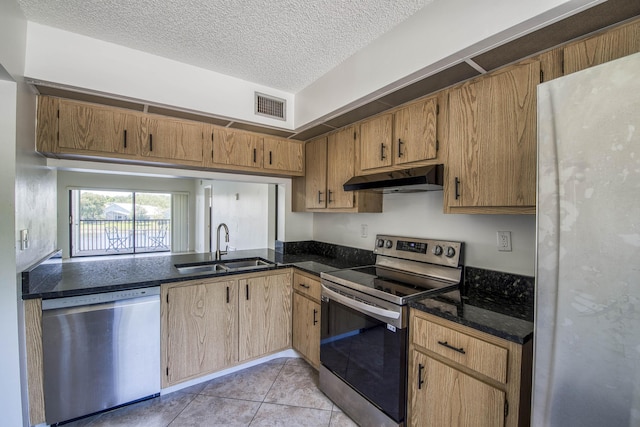 kitchen featuring stainless steel appliances, under cabinet range hood, a sink, light tile patterned floors, and a textured ceiling