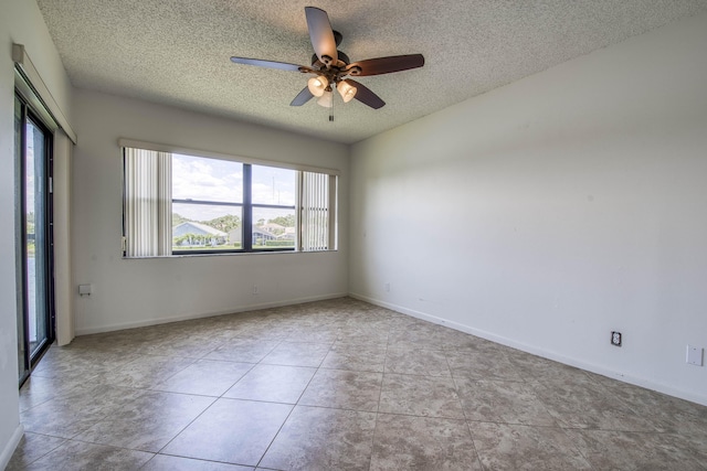 spare room featuring a textured ceiling, a ceiling fan, tile patterned flooring, and baseboards