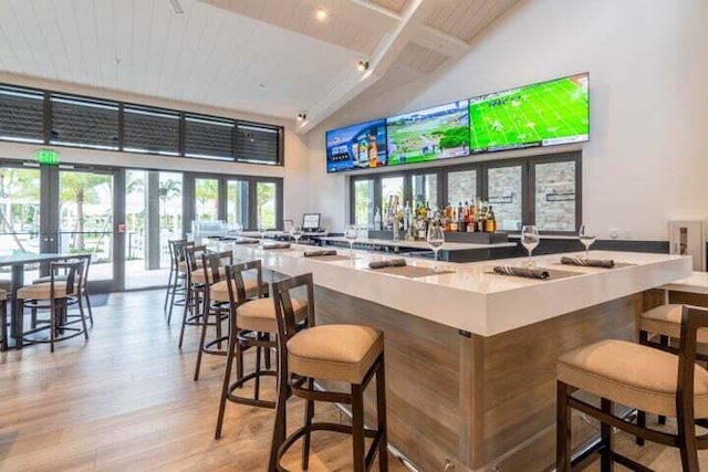 bar with high vaulted ceiling, french doors, light wood-style floors, and wood ceiling with exposed beams