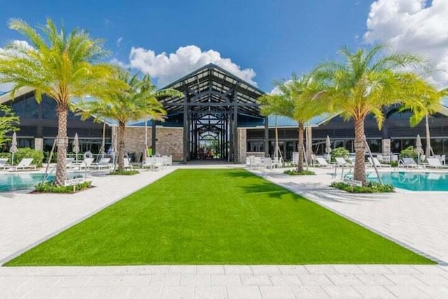 rear view of house with a community pool, a patio, and a yard