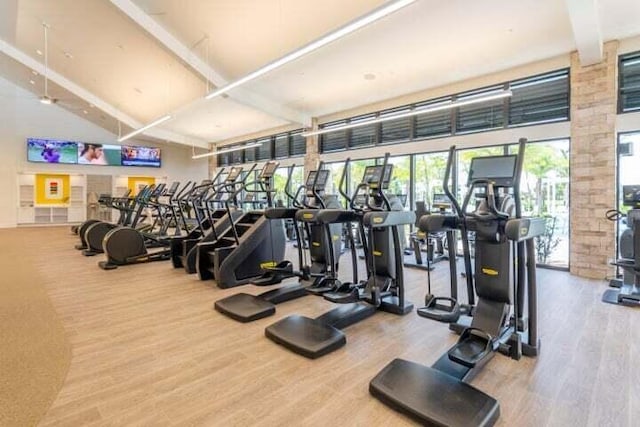 workout area featuring beam ceiling and wood finished floors