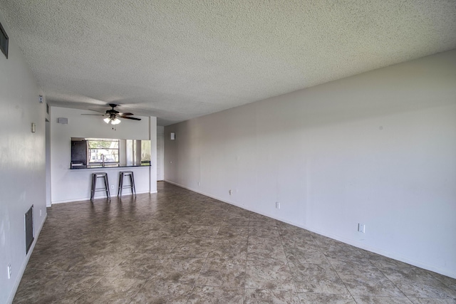 unfurnished living room with a ceiling fan and a textured ceiling