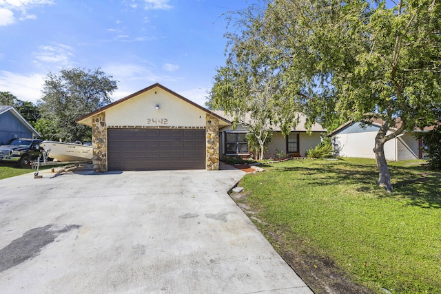 2442 SW Lafayette St, Port Saint Lucie, FL 34984 - view of front of home featuring an attached garage, a front lawn, stone siding, and concrete driveway