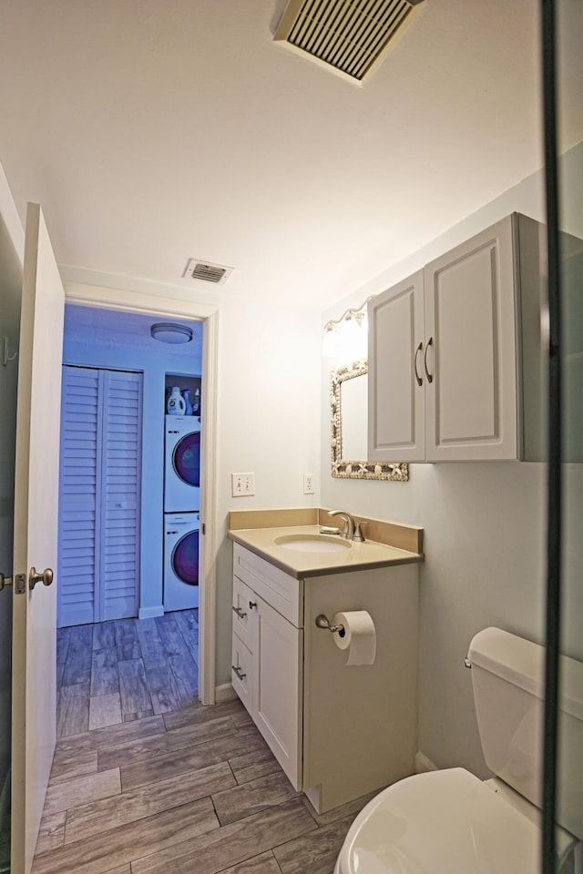 2950 SE Ocean Blvd Unit 127-8, Stuart, FL 34996 - bathroom with stacked washer / dryer, vanity, wood finished floors, and toilet