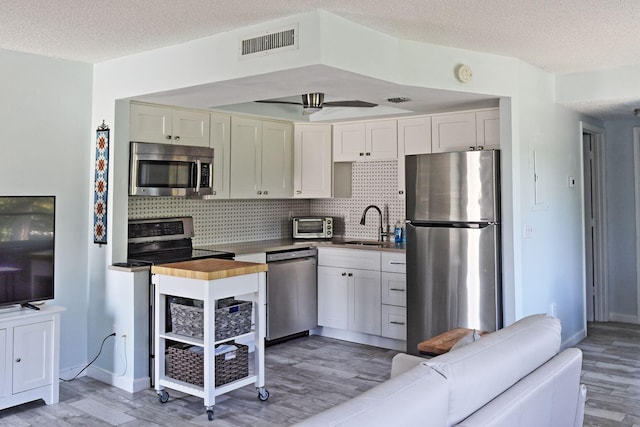 2950 SE Ocean Blvd Unit 127-8, Stuart, FL 34996 - kitchen featuring stainless steel appliances, light wood finished floors, backsplash, a sink, and a textured ceiling